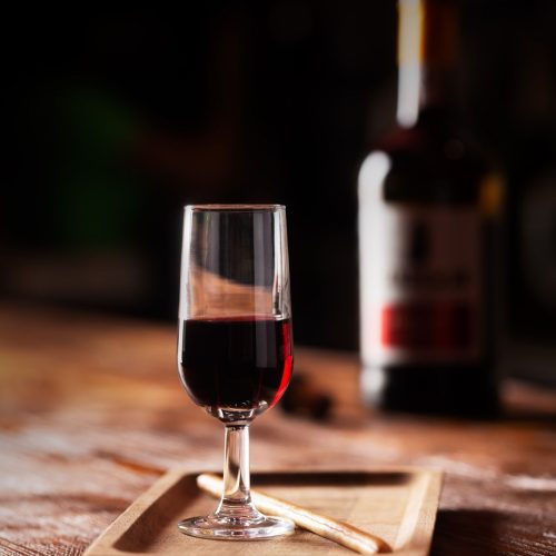 Glass of Port Wine on Wooden Table Over Dark Background